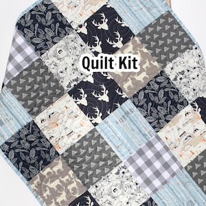May include: A quilt kit featuring a variety of fabrics with woodland animal and geometric patterns in shades of blue, grey, black, and white. The text "Quilt Kit" is visible in the centre of the image.