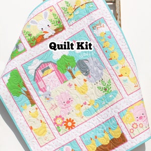May include: A quilt kit featuring a farm animal theme with a pink barn, chickens, pigs, a bunny, and a cow. The quilt kit includes a variety of fabrics in pink, blue, yellow, and green. The text "Quilt Kit" is printed on the fabric.