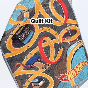 May include: A quilt kit featuring a Hot Wheels race track design. The quilt is made of blue, yellow, red, and black fabric. The kit includes all the fabric needed to make a quilt. The quilt is perfect for a child's room or playroom.