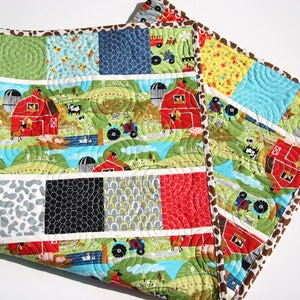 Farm baby quilt pattern featuring red barn fabrics, tractors, cows, and colorful charm square patchwork strips in a modern nursery quilt.