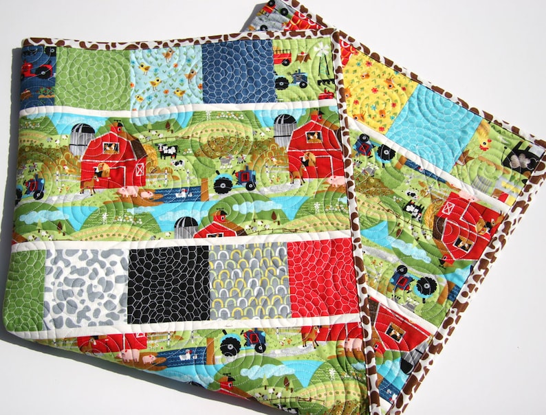 Farm baby quilt pattern featuring red barn fabrics, tractors, cows, and colorful charm square patchwork strips in a modern nursery quilt.