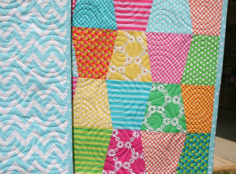 Bright and cheerful Tumbled quilt pattern made with colorful charm square fabrics in pink, turquoise, orange, lime, yellow, and purple tones. This easy PDF quilt pattern by Kristin Blandford Designs is perfect for beginner quilters looking for a fun baby quilt pattern, modern lap quilt design, or fast sewing project using 5 inch precuts.