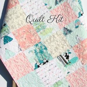 May include: A quilt kit featuring a patchwork design with various patterns and colors, including pink, green, white, and gray. The quilt features a panda bear design and the text "Quilt Kit".
