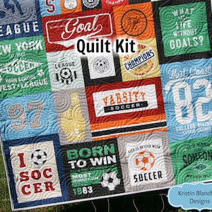 May include: A quilt kit featuring a variety of colourful fabric squares with football-themed designs and text, including "Goal", "Varsity Soccer", "Born to Win", "I Soccer", and "What is life without goals?"