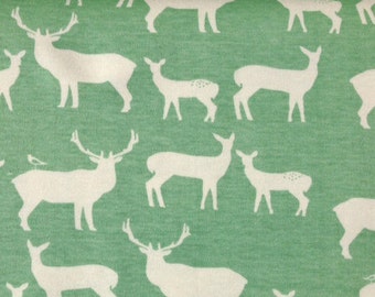 May include: A green fabric with a white repeating pattern of deer silhouettes. The deer are in various poses, including standing, running, and jumping.