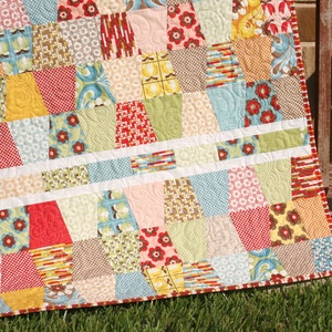 Colorful geometric quilt made with bright precut fabrics and modern tumbling block piecing in a beginner friendly quilt pattern format. This digital quilt pattern by Kristin Blandford Designs includes easy to follow instructions for creating modern baby quilts, throw quilts, and cheerful patchwork blankets using charm squares.