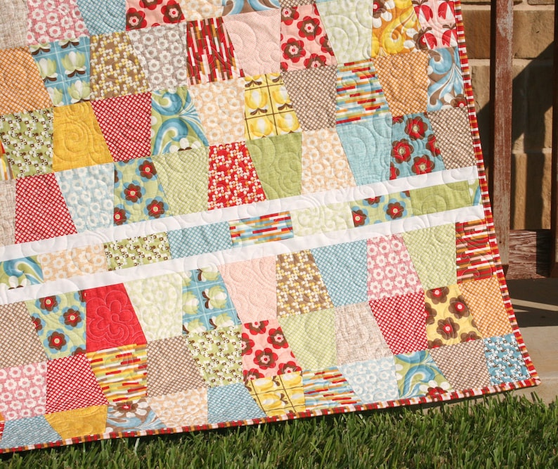 Colorful geometric quilt made with bright precut fabrics and modern tumbling block piecing in a beginner friendly quilt pattern format. This digital quilt pattern by Kristin Blandford Designs includes easy to follow instructions for creating modern baby quilts, throw quilts, and cheerful patchwork blankets using charm squares.