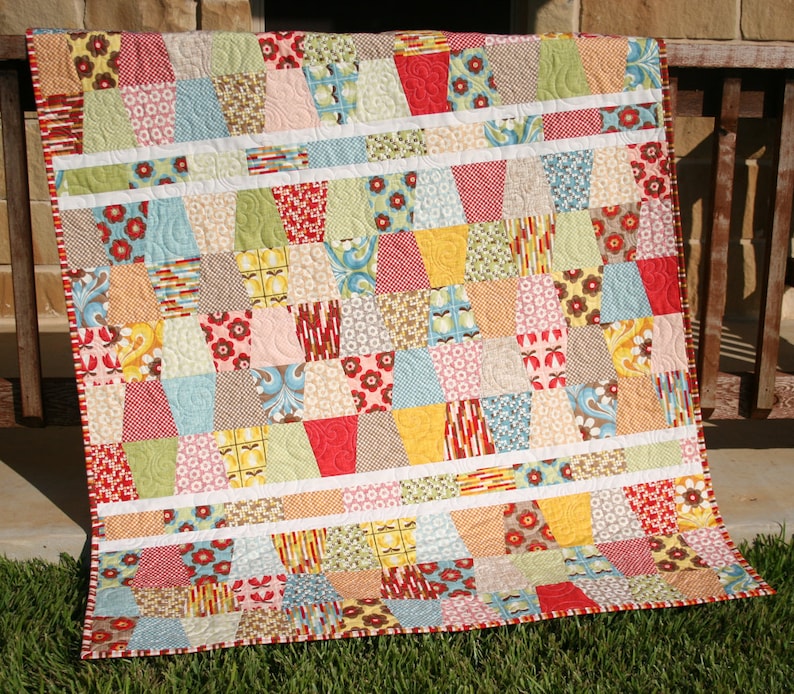 Fun and easy Tumbled quilt pattern featuring bright rainbow inspired patchwork blocks made from charm pack squares and precut quilting fabrics. This digital PDF sewing pattern by Kristin Blandford Designs is beginner friendly and ideal for fast quilt finishes, colorful baby blankets, and modern throw quilt projects.