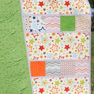 Modern nursery quilt pattern featuring stars fabrics and colorful charm square patchwork for handmade baby shower gifts.