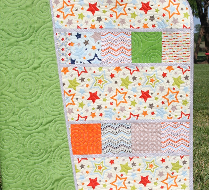 Modern nursery quilt pattern featuring stars fabrics and colorful charm square patchwork for handmade baby shower gifts.