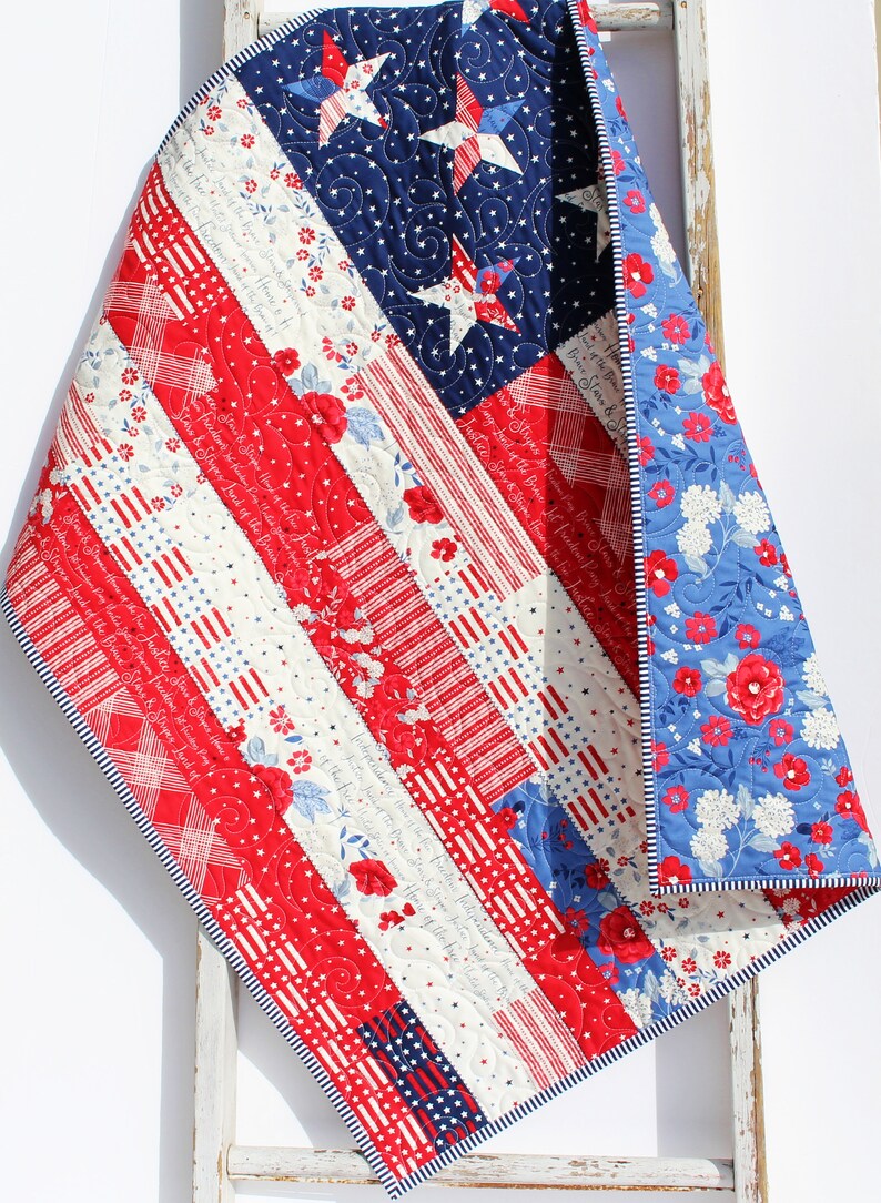 May include: A red, white, and blue patchwork quilt with a star pattern on the blue section. The quilt is folded and draped over a white wooden ladder.
