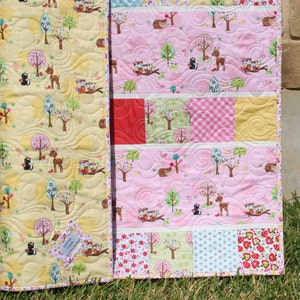 Showcase baby quilt pattern using 5 inch precut squares and charm packs with pastel patchwork blocks and soft pink nursery fabrics.