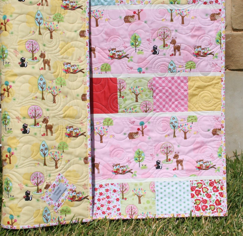 Showcase baby quilt pattern using 5 inch precut squares and charm packs with pastel patchwork blocks and soft pink nursery fabrics.