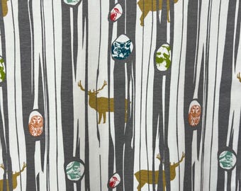May include: A white fabric with a repeating pattern of gray tree trunks, colorful owls, deer, and geometric shapes. The background is white with a subtle texture.