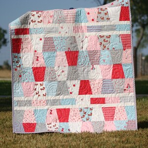 Tumbled PDF quilt pattern for baby quilts and lap quilts featuring bold colorful patchwork blocks arranged in a playful tumbling design. This beginner friendly sewing pattern from Kristin Blandford Designs is ideal for charm packs, 5 inch squares, stash busting quilts, nursery decor, and handmade baby shower gifts.