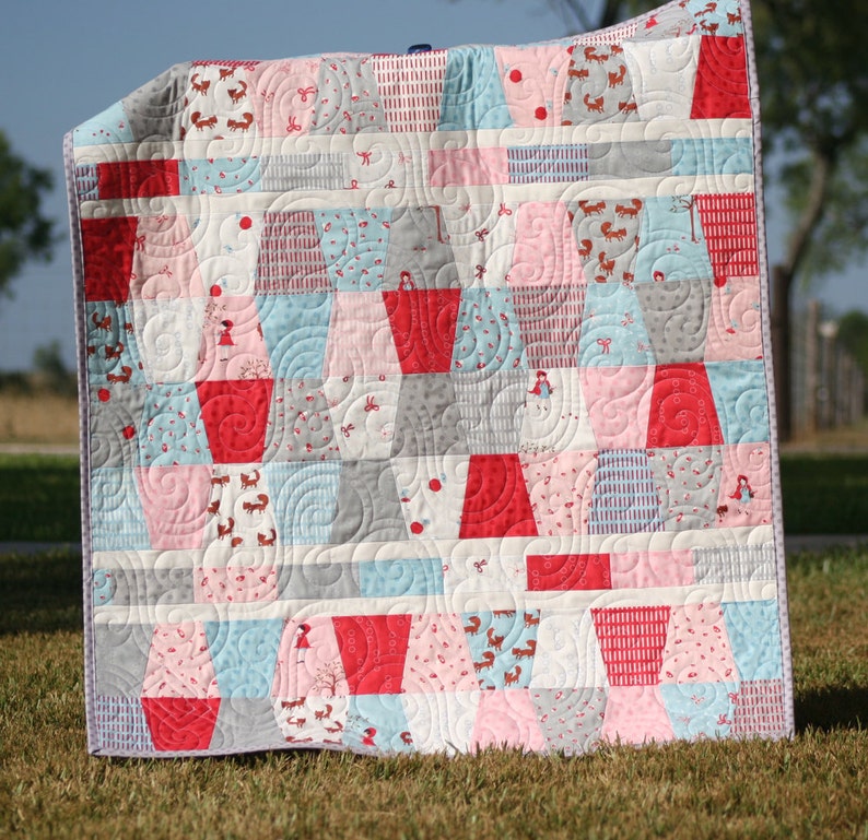 Tumbled PDF quilt pattern for baby quilts and lap quilts featuring bold colorful patchwork blocks arranged in a playful tumbling design. This beginner friendly sewing pattern from Kristin Blandford Designs is ideal for charm packs, 5 inch squares, stash busting quilts, nursery decor, and handmade baby shower gifts.