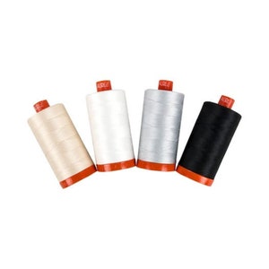 May include: Four spools of thread in different colors: beige, white, silver, and black. The spools are all the same size and have a red label with the word "AURIOL" on them.