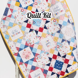May include: A quilt kit featuring a patchwork design with various colors and patterns. The quilt is made up of squares with different phrases embroidered on them, including "good vibe tribe", "be the sunshine", "love your self", "make today awesome", and "choose joy".
