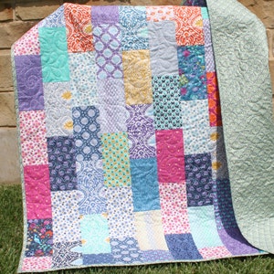 Modern patchwork quilt pattern PDF featuring bold geometric quilt blocks and colorful fabric placement perfect for beginner quilting projects