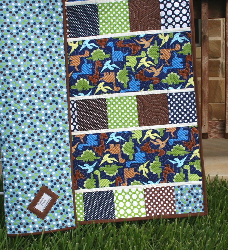 Easy PDF baby quilt pattern with whimsical dinosaur fabrics, polka dot charm squares, and clean strip piecing for beginner quilting projects.