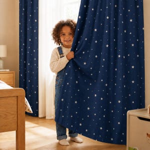 May include: A pair of floor-length curtains in a deep navy blue color featuring a repeating pattern of small white stars. The fabric is opaque and hangs in vertical folds, covering a window area to provide light filtration and privacy.