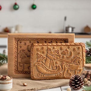 May include: A light brown gingerbread biscuit featuring a detailed Santa Claus and sleigh design, alongside a wooden mould with a matching embossed pattern. The biscuit shows Santa Claus in his sleigh. The wooden mould is also light brown, perfect for festive baking.
