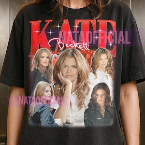 Puede incluir: Camiseta negra con un gráfico de Kate Beckett y el texto "KATE Beckett" en rojo. El diseño incluye múltiples imágenes del personaje. El texto "NATAOFFICIAL" también es visible.