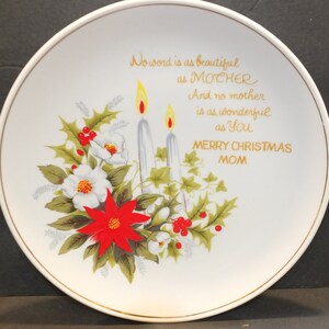 May include: White ceramic plate with a gold rim and a Christmas-themed design. The plate features a poinsettia, holly, and two candles with a message that reads "No word is as beautiful as MOTHER And no mother is as wonderful as You MERRY CHRISTMAS MOM".