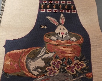 May include: A tapestry vest panel with a blue background featuring two white rabbits in flower pots. The top of the panel has a pink rabbit and a border of red hearts and orange carrots.