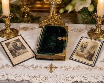 May include: A dark green velvet book with gold metal corners and a central clasp, flanked by two rectangular religious prints on a white embroidered cloth, positioned between two tall brass candlesticks with lit white candles.