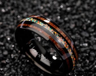 May include: Black ring with a wood grain and opal inlay. The ring has the words "I love you" engraved on the inside. The opal inlay features a variety of colors, including green, orange, and yellow.