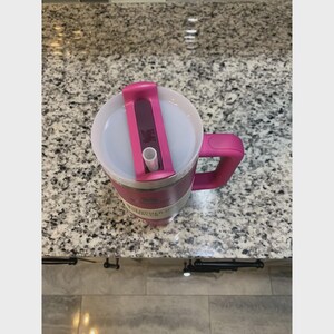 Puede incluir: Un vaso t&eacute;rmico rosa con asa y tapa. La tapa tiene un cierre deslizante y una abertura para pajita. El vaso es de acero inoxidable y tiene un asa rosa. Dise&ntilde;ado para mantener las bebidas calientes o fr&iacute;as.
