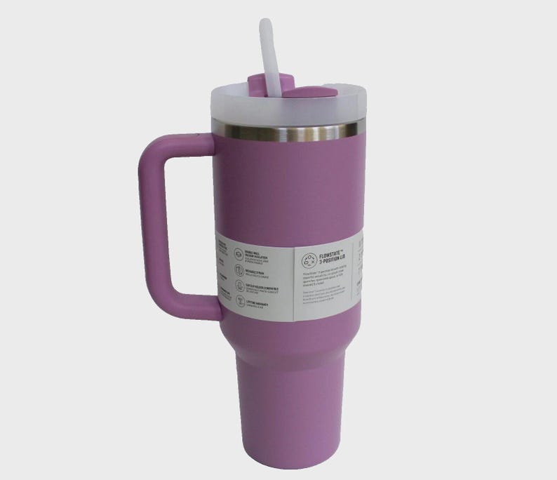May include: A large, lavender insulated tumbler with a handle and a white lid. The tumbler has a stainless steel rim and a white straw. A label with text is visible on the side.