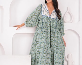 Può includere: Abito con stampa floreale verde chiaro con scollo a V e maniche lunghe. L'abito presenta un pannello bianco con bordatura blu intorno allo scollo. L'abito, lungo fino al ginocchio, ha una vestibilità ampia, adatta all'abbigliamento casual.