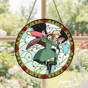 May include: Round stained glass window featuring a couple from the animated film, Howl's Moving Castle. The design includes a green dress, black wings, and red roses around the edge. The window is suspended by a metal chain.