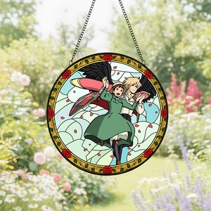 May include: Round stained glass window featuring a cartoon couple with wings, set against a light blue sky with falling petals. The border is gold with red roses. The window hangs from a chain.