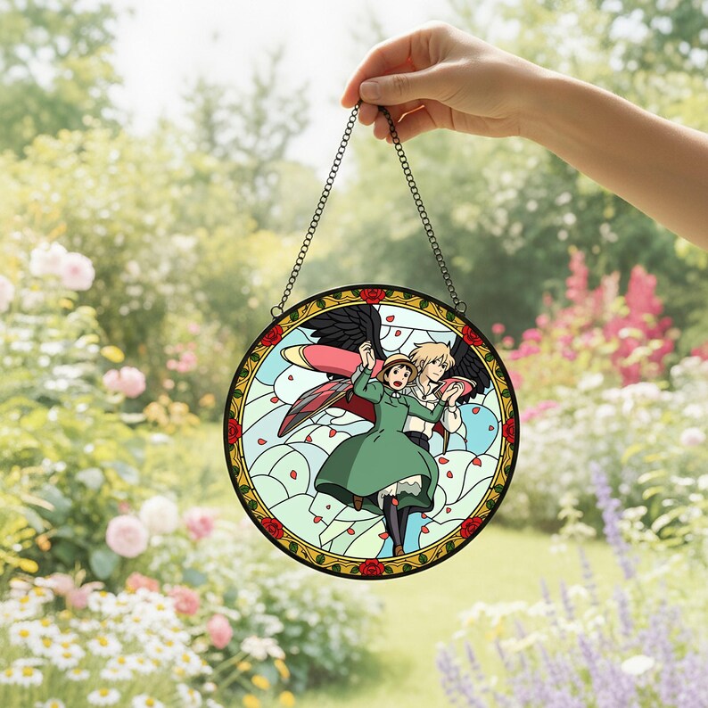 May include: A round stained glass window featuring a cartoon couple with wings, set against a light blue sky with red rose accents. The window is framed with a gold border and a black chain for hanging.