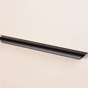 Op de afbeelding: Een zwarte, cilindrische kastgreep is horizontaal op een lichtgekleurde kastdeur gemonteerd. De greep heeft een gladde, matte afwerking en een minimalistisch ontwerp, wat zorgt voor een strakke, moderne uitstraling. De greep is ongeveer 25 cm lang.