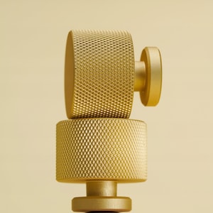 Könnte beinhalten: Goldfarbenes, strukturiertes Metallobjekt mit zylindrischem Sockel und abgerundeter Oberseite. Die Oberseite hat ein Rautenmuster. Das Objekt befindet sich vor einem hellgelben Hintergrund. Das Gesamtdesign ist modern und minimalistisch.