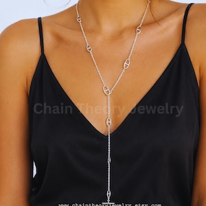 May include: A silver-toned Y-shaped lariat necklace featuring a delicate cable chain interspersed with several oval-shaped links, each containing a horizontal bar. The necklace terminates in a small horizontal bar toggle clasp at the bottom.