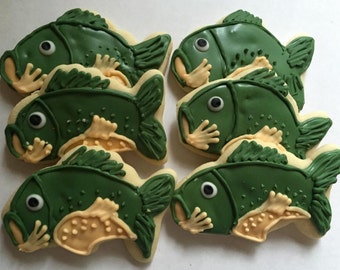 May include: Six green and yellow decorated sugar cookies shaped like bass fish.