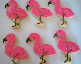 May include: Six pink flamingo-shaped sugar cookies with black icing details. The cookies are decorated with a pink icing base and black icing for the eyes, beak, and legs.
