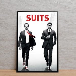 May include: A framed poster featuring two men in suits. The word "SUITS" is in red block letters at the top. One man wears a red tie and red sneakers. The other man wears a black tie and black shoes. The background is a grayscale image of a city.