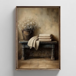 May include: A framed painting depicts a still life scene. A rustic wooden bench holds folded towels and a draped cloth. A metal bucket with flowers sits atop the bench. The color palette is muted with beige, brown, and blue tones.
