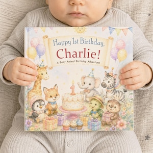 May include: A hardback children's book titled Happy 1st Birthday, Charlie! A Baby Animal Birthday Adventure. The cover features a watercolour illustration of a giraffe, fox, penguin, elephant, zebra, and turtle with birthday gifts and a cake.