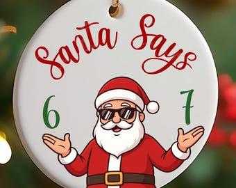 May include: A round Christmas ornament with the text "Santa Says" in red script. Santa Claus, wearing sunglasses, a red suit, and a white beard, is in the center. Green numbers 6 and 7 flank Santa.