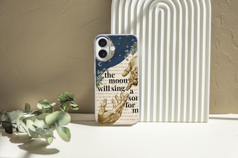 Pode incluir: Capa de telefone transparente com um design celestial, incluindo uma lua crescente e estrelas. A capa tem uma est&eacute;tica vintage com uma colagem de m&atilde;os e o texto "the moon will sing a sor for m".