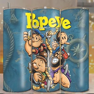 May include: A blue tumbler featuring the cartoon character Popeye and friends. The word "Popeye" is in yellow block letters. The design includes images of Popeye, Olive Oyl, and other characters, with nautical elements.