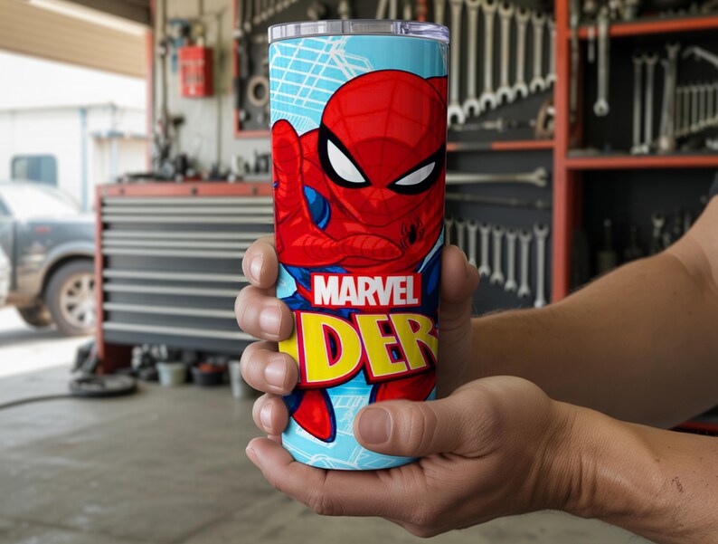 Pu&ograve; includere: Un bicchiere cilindrico con Spider-Man. Il bicchiere ha uno sfondo azzurro con una grafica di Spider-Man rossa e blu. Le parole "MARVEL" e "DER" sono in giallo e rosso. Il bicchiere &egrave; tenuto tra le mani di una persona.