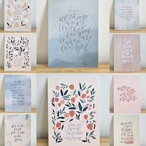 May include: Nine art prints with motivational quotes and floral designs. The prints showcase a range of colours, including pastel pinks, blues, and greens. Some prints feature text such as "All things work together for good" and "Trust in Jesus."